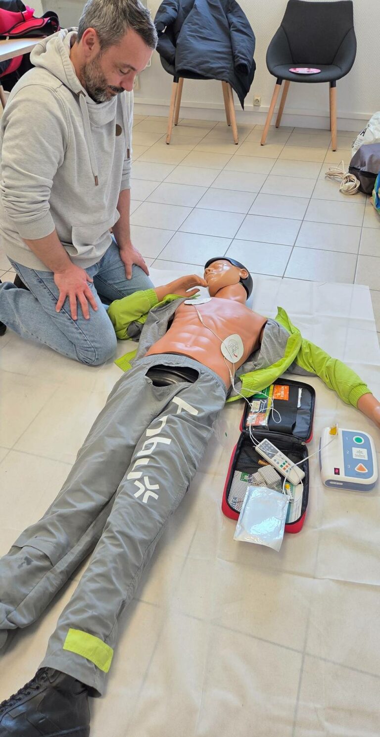 Exercice pratique de réanimation cardio-pulmonaire (RCP) et utilisation d'un défibrillateur (DAE) sur mannequin lors d'une formation SST Ignaxis pour PRIVÉ SA à Châlons-en-Champagne.
